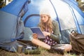 Pretty blonde camper using tablet and sitting in tent Royalty Free Stock Photo