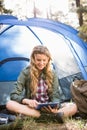 Pretty blonde camper using tablet and sitting in tent Royalty Free Stock Photo