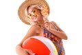 Pretty blonde caucasian female stands in swimsuit with big rubber beach colourful ball, lolipop and smiles isolated on