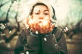 Pretty blonde girl blowing white petals from hands. apricot flowers