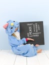 Pretty blonde girl with cozy blue unicorn costume with blackboard with different words on it like love and peace and some more