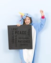 Pretty blonde girl with cozy blue unicorn costume with blackboard with different words on it like love and peace and some more