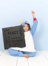 Pretty blonde girl with cozy blue unicorn costume with blackboard with different words on it like love and peace and some more