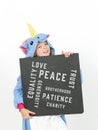 Pretty blonde girl with cozy blue unicorn costume with blackboard with different words on it like love and peace and some more