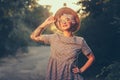 Pretty blonde girl with short haircut is posing and smiling to the camera in forest on sunset background. She wears hat Royalty Free Stock Photo