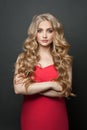 Pretty blonde hair woman wearing red dress standing with crossed arms on black background Royalty Free Stock Photo