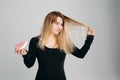 Pretty woman holding messy hair in one hand and hairbrush in another one. Royalty Free Stock Photo