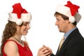 Pretty blonde lady smiling in santa hat getting ring from young man
