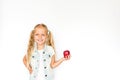 Pretty blonde little girl standing on white background and holding fresh red apple. Healthy food concept Royalty Free Stock Photo