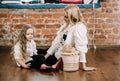 Pretty blonde mother and her caucasian little daughter sitting on the floor with big box gift and happy together Royalty Free Stock Photo