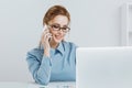 Pretty blonde office girl talking phone at her workplace. Royalty Free Stock Photo