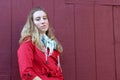 Pretty blonde in red jacket against red barn wall