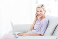 Pretty blonde woman calling on the phone and using her laptop Royalty Free Stock Photo