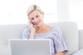 Pretty blonde woman calling on the phone and using her laptop Royalty Free Stock Photo