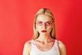 Pretty blonde woman with creative fashionable makeup on red background