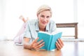 Pretty blonde woman lying on the floor and reading a book Royalty Free Stock Photo