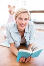 Pretty blonde woman lying on the floor and reading a book Royalty Free Stock Photo