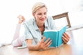 Pretty blonde woman lying on the floor and reading a book Royalty Free Stock Photo