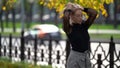 Pretty blonde woman in park area at fall day, portrait of female city dweller at good autumn weather