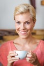 Pretty blonde woman smiling at camera and holding a cup of coffee Royalty Free Stock Photo