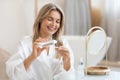 Pretty blonde woman using face tonner, looking at mirror Royalty Free Stock Photo