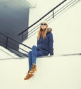 Pretty blonde woman wearing a jacket, hat and sunglasses sitting Royalty Free Stock Photo