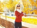 Pretty blonde woman wearing sunglasses and red jacket with scarf in sunny autumn Royalty Free Stock Photo