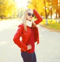 Pretty blonde woman wearing a sunglasses and red jacket with scarf in sunny autumn Royalty Free Stock Photo