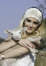 Pretty blonde woman with white crochet headband holding little lamb Royalty Free Stock Photo