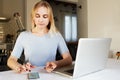Pretty blond woman working at home on laptop.