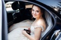 Pretty bride checks her phone while sitting in the car Royalty Free Stock Photo