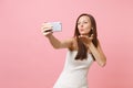 Pretty bride woman in white wedding dress blowing lips, sending air kiss, doing taking selfie shot on mobile phone Royalty Free Stock Photo