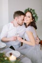 Pretty bridesmaid in pine wreath and groomman at the wedding table hugging and kissing. Group of people sitting at