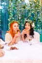 Pretty bridesmaids in floral wreaths on heads are eating tasty burgers and smiling. Rustic wedding outdoors