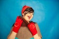 Pretty brunette girl wearing fashion red knitted winter gat and warm beautiful gloves on blue studio solid background Royalty Free Stock Photo