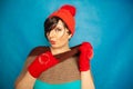 Pretty brunette girl wearing fashion red knitted winter gat and warm beautiful gloves on blue studio solid background Royalty Free Stock Photo