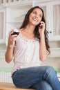 Pretty brunette on the phone having glass of wine