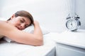 Pretty brunette sleeping in bed with alarm clock Royalty Free Stock Photo