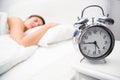 Pretty brunette sleeping in bed with alarm clock Royalty Free Stock Photo