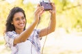 Pretty brunette taking a selfie with retro camera in the park Royalty Free Stock Photo