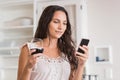 Pretty brunette using smartphone and having glass of wine Royalty Free Stock Photo