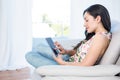 Pretty brunette using tablet on couch Royalty Free Stock Photo