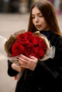 Pretty brunette woman with a bouquet of dark red roses Royalty Free Stock Photo