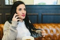 Pretty brunette woman checking her smartphone while having breakfast drinking coffee in a retro restaurant