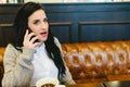 Pretty brunette woman checking her smartphone while having breakfast drinking coffee in a retro restaurant