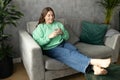 Pretty brunette woman drinking water on couch at home in the living room. 30s female rest and spend free spare time Royalty Free Stock Photo