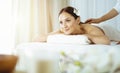 Pretty brunette woman enjoying treatment with hot stones in sunny spa salon. Beauty concept. Cold toned picture