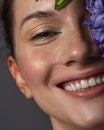 Pretty brunette woman with red creative make up and blue hyacinth flower near her face. Close up beauty concept with studio