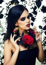 Pretty brunette woman with rose jewelry, black and red, bright make up kike a vampire closeup red lips Royalty Free Stock Photo