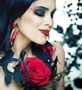 Pretty brunette woman with rose jewelry, black and red, bright make up kike a vampire closeup red lips Royalty Free Stock Photo